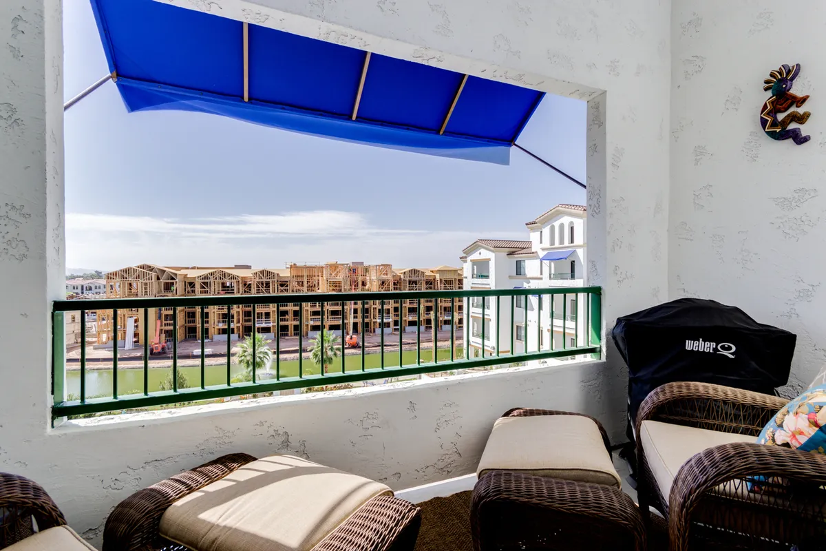 An inviting outdoor kitchen and grilling area featuring a Weber grill, comfortable outdoor seating, and striking views over the water and nearby buildings. The space is designed for both casual meals and evening social gatherings, capturing the spirit of resort-style outdoor living.