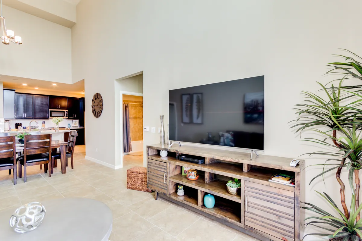 An inviting interior scene with a cozy living space, wooden entertainment unit, TV, visible dining area, and lush indoor plants. The setup is designed for both relaxed family gatherings and festive entertaining, with a clear view of how the living and dining spaces interconnect.