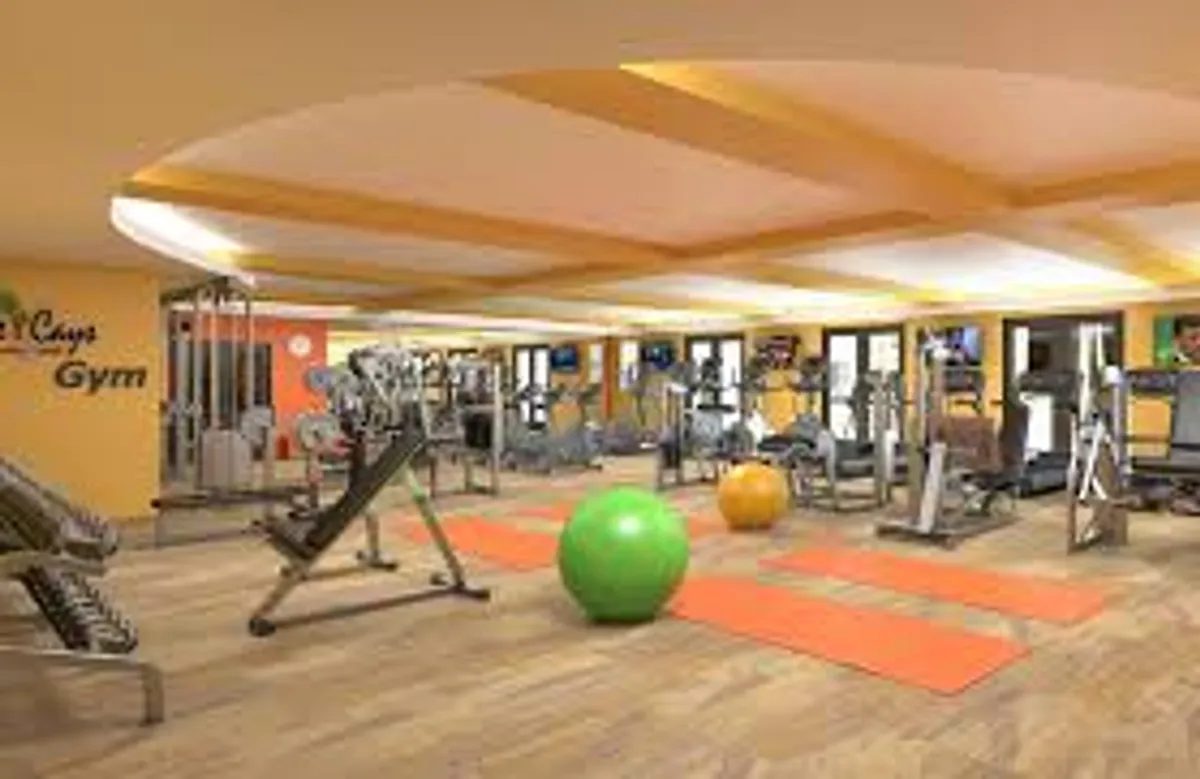 A modern, well-equipped fitness center filled with exercise machines, colorful exercise balls, yoga mats, and expansive windows that let in natural light. The space feels energizing yet welcoming, ideal for both solo workouts and group fitness or yoga sessions.